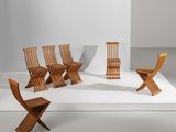 Plusieurs chaises en bois sont alignées sur une surface blanche