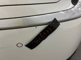 the back end of a white car with a sticker on it ' s bumper