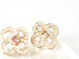 pair of gold tone flower earrings with clear crystals on a white surface
