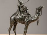bronze statue of a man riding a camel with a spear in his hand
