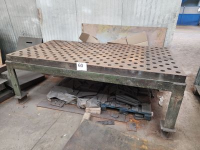 une table en métal percée de trous, au milieu d'une pièce