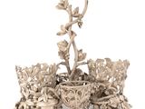 a silver candle holder with flowers and leaves on it