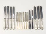 six silverplated knives and six knives on a white surface