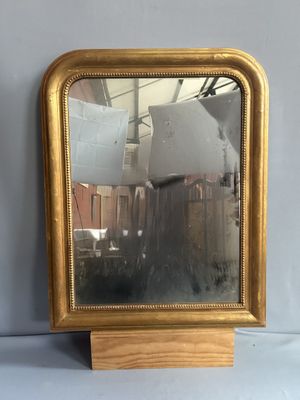 un miroir posé sur un support, lui-même posé sur une table