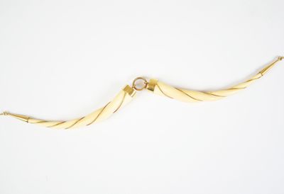 an image of a gold necklace with a curved design on it