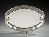 an antique silver plate on a stand on a gray surface