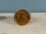 l'image d'une bague en or sur laquelle se trouve une pièce de monnaie