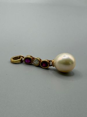 une image représentant une broche ornée de perles et de diamants posée sur un fond gris