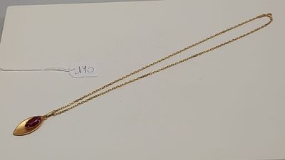 un gros plan d'un collier en or orné d'une pierre rouge