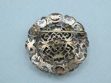 an antique silver broochle with filigree design on a white surface