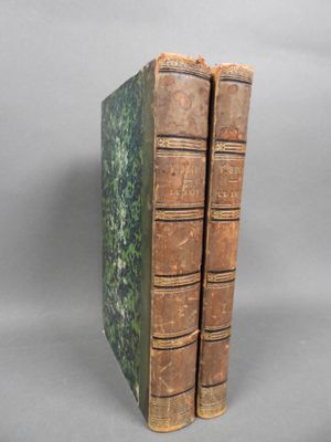 two old books sitting on top of each other on a gray surface