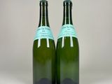 two bottles of wine sitting next to each other on a white surface