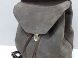 grey backpack with brown leather straps on a white surface