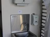 a stainless steel sink and a towel dispenser on the wall