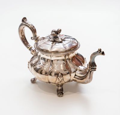 une théière ancienne en argent avec son couvercle, sur fond blanc