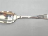 silver plated spoon on a gray surface with a reflection of a person in the mirror