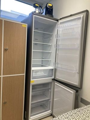 an empty refrigerator in the corner of a room with a bed