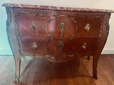 a marble top chest of drawers on a wooden floor
