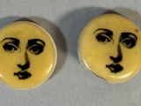 two yellow buttons with faces painted on them sitting on a table