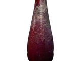 un vase rouge posé sur une surface blanche