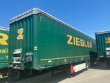 two green semi trailers parked next to each other on the street