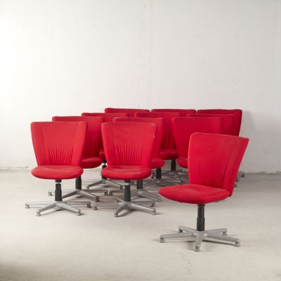 six chaises de bureau rouges dans une pièce aux murs blancs