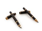 une paire de stylos à plume noir et or sur une surface blanche