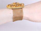 someone is wearing a gold bracelet with a golden flower design on it