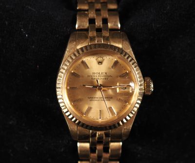 gold rolex watch on a black velvet surface with a black background