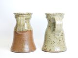 two small vases sitting side by side on a white surface
