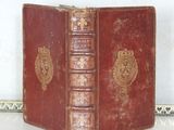 a red book with gold trim sitting on a white table