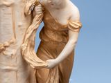 a figurine of a woman leaning against a tree