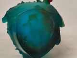 a blue glass object with a red flower on top of it
