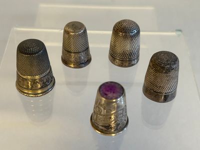 Plusieurs dés à coudre sont exposés sur une surface en verre