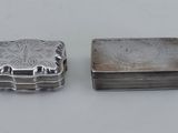 deux petites boîtes en argent posées l'une à côté de l'autre sur une table