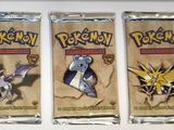 three packs of pokemon trading cards sitting on top of a table