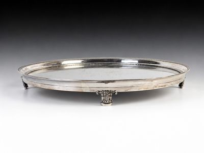 a silver plate with a handle on a stand on a table