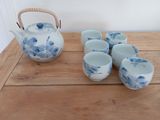 several cups and a teapot on a wooden table with a tea kettle