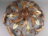 une décoration murale en métal ornée de feuilles dorées et d'un bouton marron