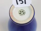 a small blue vase with a white label on it