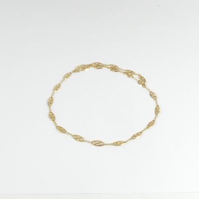gros plan d'un bracelet en or sur une surface blanche