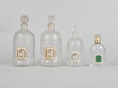 quatre bouteilles en verre sont alignées sur une surface blanche