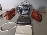 several purses are lined up on a table in front of a white wall