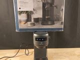 an electric coffee grinder sitting on top of a wooden table next to a box