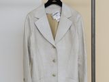 une veste grise accrochée à un porte-vêtements devant un mur blanc