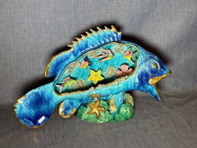 une figurine de poisson bleue posée sur un socle vert