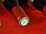 three bottles of red wine are lined up on a red cloth