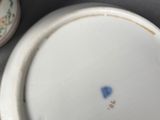 a white plate with a blue flower on it next to a bottle of mustard