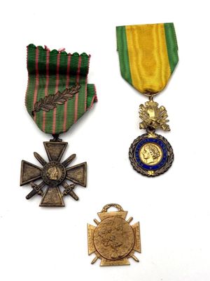 three medals and a cross are on a white surface