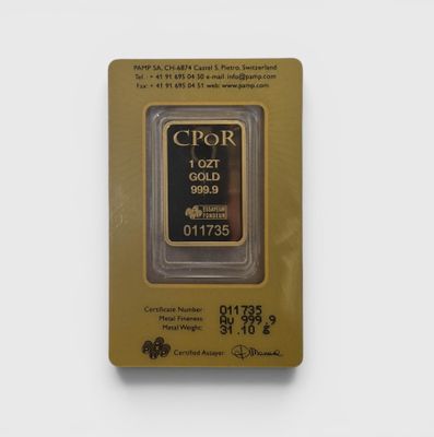 un gros plan d'un lingot d'or dans un emballage posé sur une surface blanche